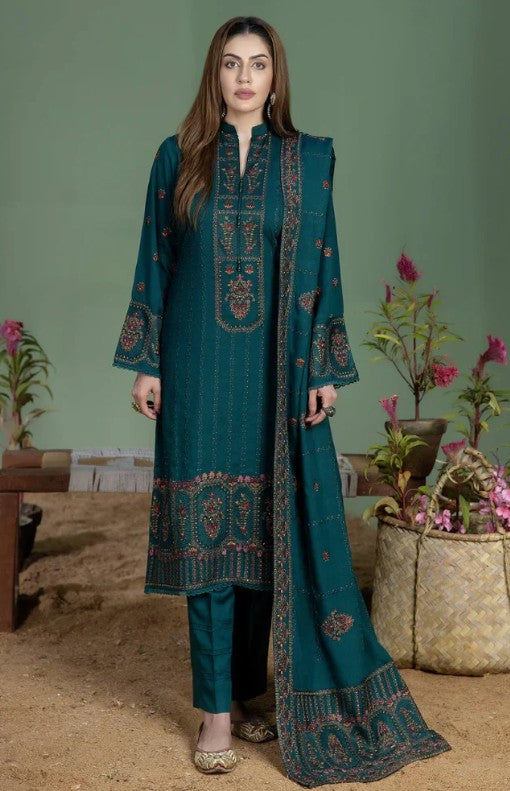 A woman modeling a traditional three-piece salwar kameez suit in deep teal green multicolor embroidery in red, gold, and beige on the kurta, pants, and matching dupatta